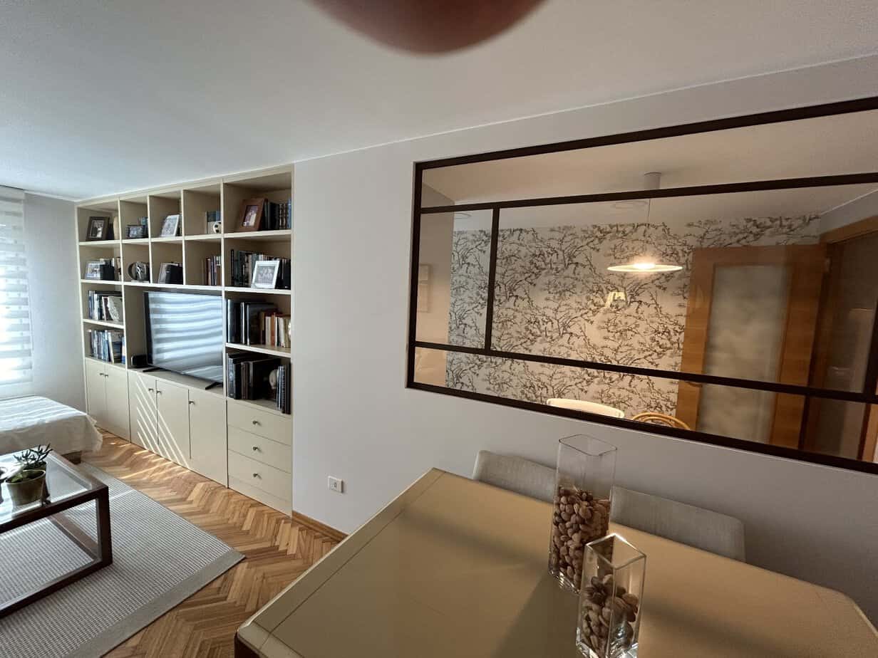 Moderno salón de reformas e interiorismo con estanterías, comedor y detalles decorativos en madera y vidrio.