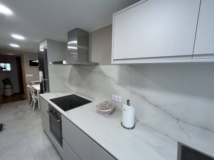 Moderno diseño de cocina con encimera de mármol gris y electrodomésticos integrados.