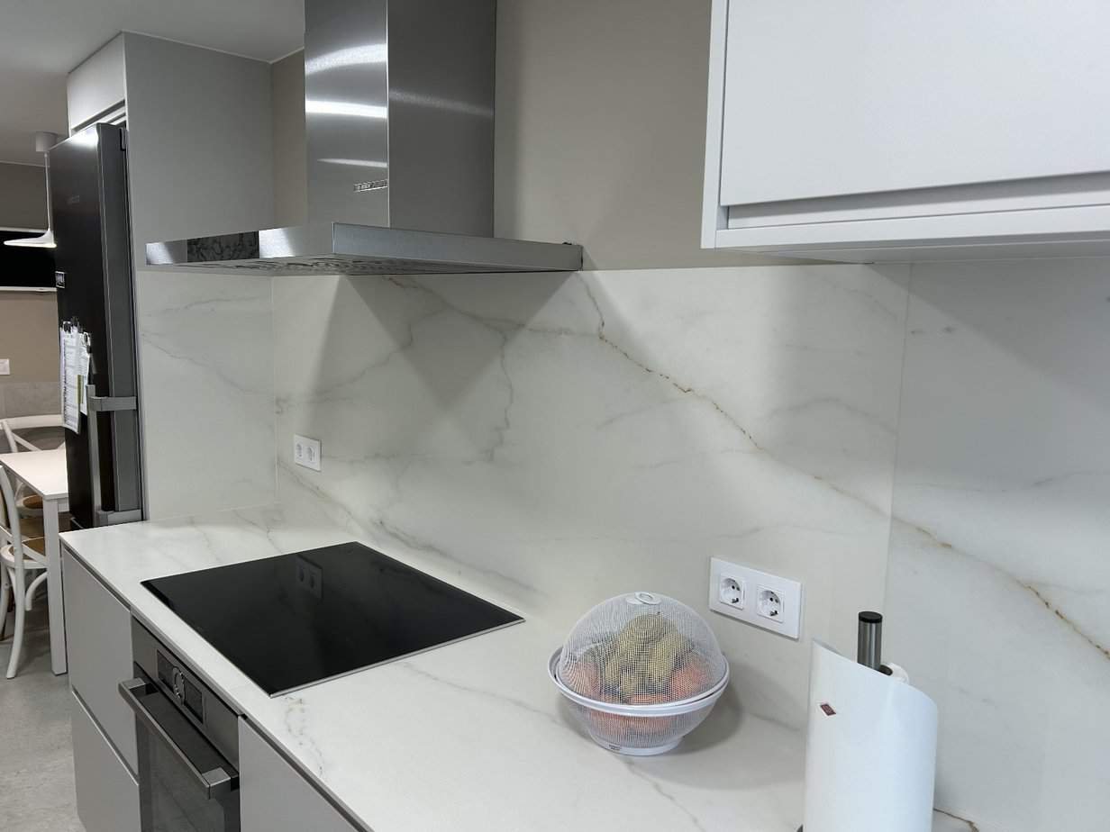 Encimera de cocina de mármol con vitrocerámica y extractor de acero inoxidable. Diseño moderno y elegante.