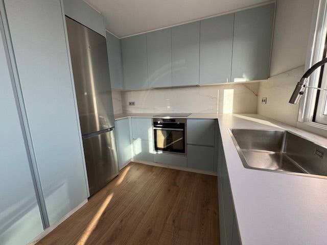 Cocina reformada en Apartamento en A Coruña Reforma de cocina moderna con electrodomésticos y acabados en tonos pastel.