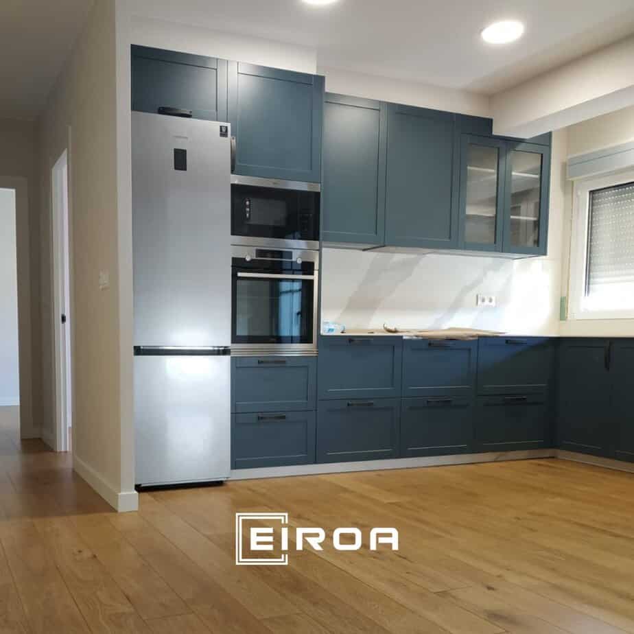 Reformas de cocina modernas con armarios azules, electrodomésticos integrados y suelo de madera elegante.